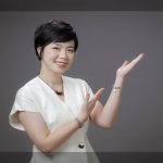 Ngô Huyền Trang áo trắng, tay giơ chào, nền xám